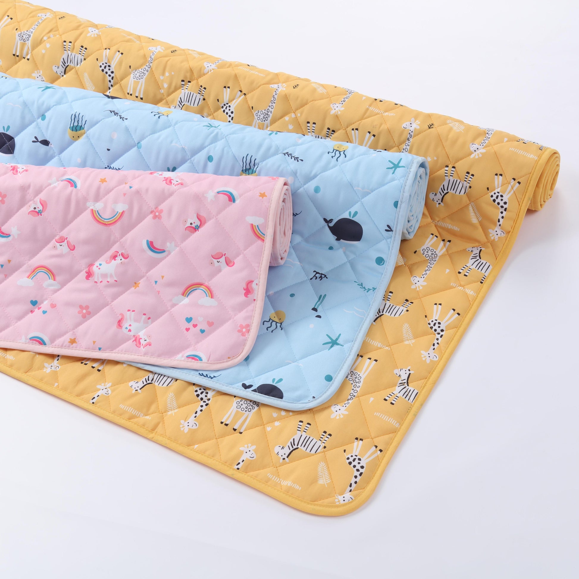 Three quilted baby blankets in yellow, pink, and blue with animal patterns on a white background.